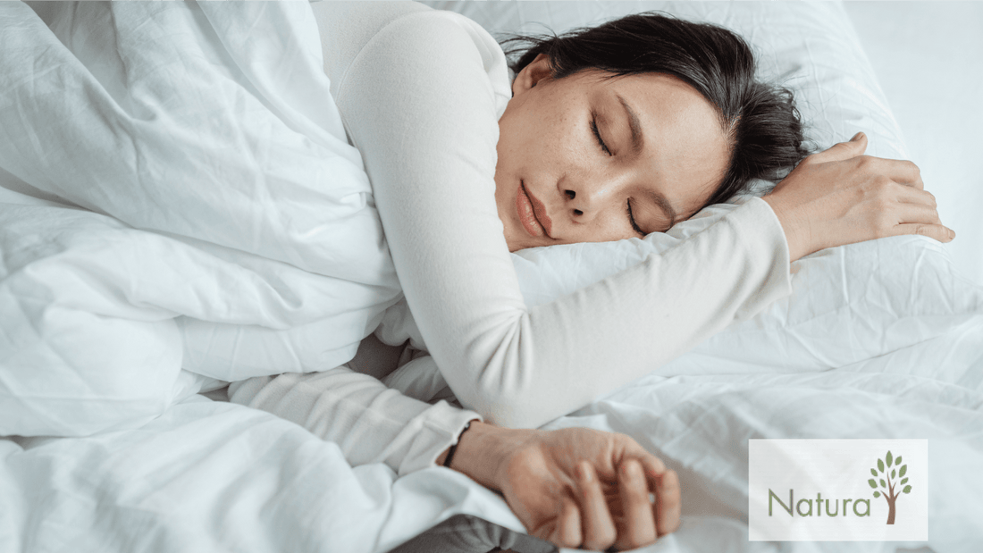 A person is comfortably resting in bed, surrounded by fluffy white bedding, with arms gently draped over pillows.