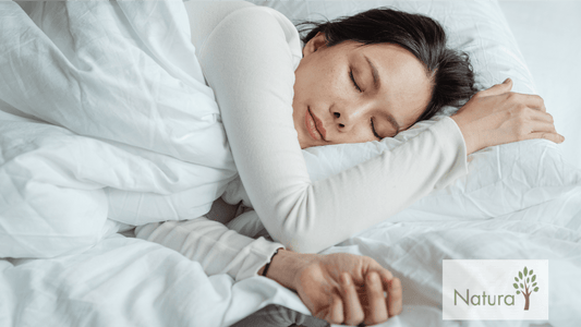 A person is comfortably resting in bed, surrounded by fluffy white bedding, with arms gently draped over pillows.