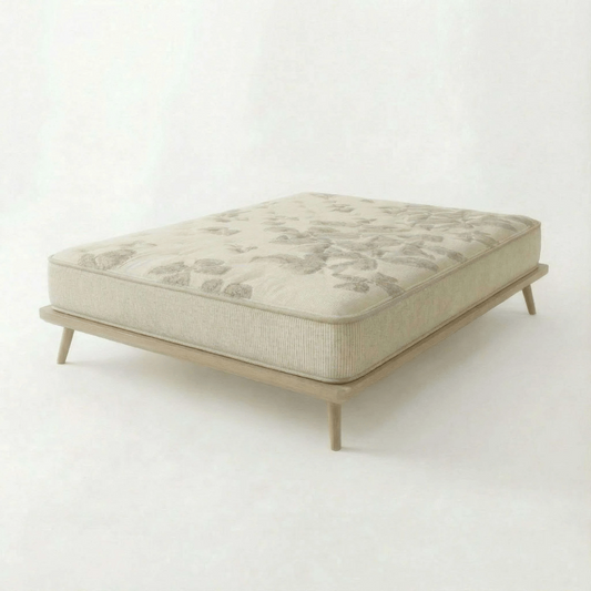 Natura Eco Haven mattress featuring a subtle leaf pattern and a light wood frame with tapered legs, set against a plain off-white background.