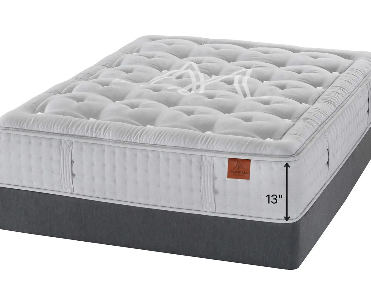 Marshall Hudson mattress with a white quilted top and side, a dark gray upholstered base, and a small brown leather brand tag. A white arrow graphic indicates a height of 13 inches against a plain white background.
