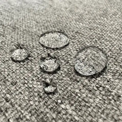 Close-up of water droplets beading on a gray Orthex waterproof fabric surface.