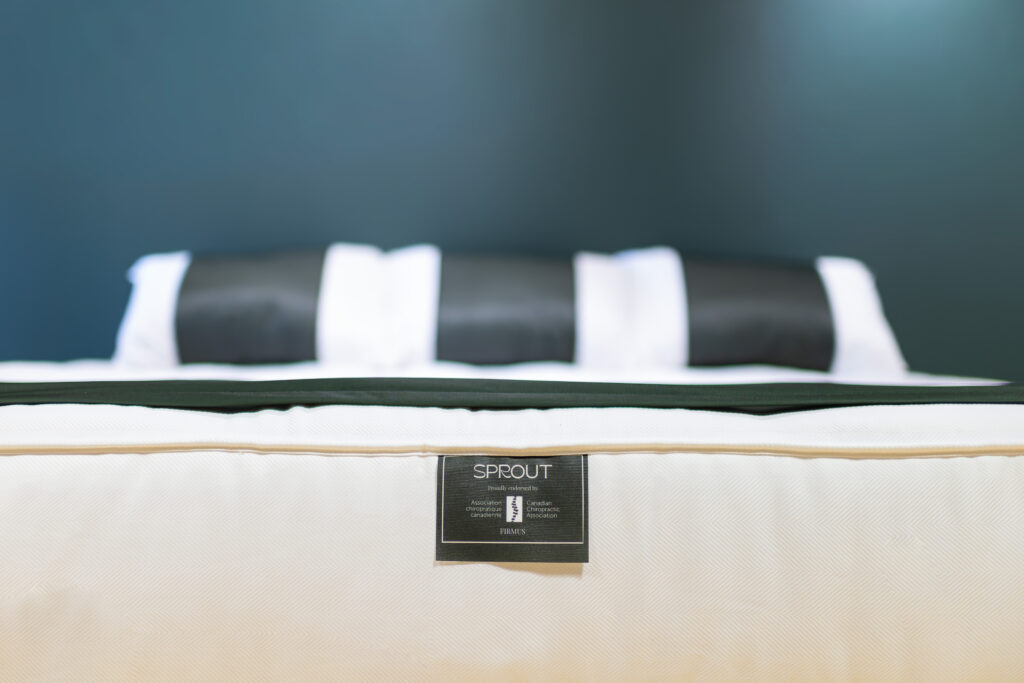 Close-up of a Sprout mattress with a brand label against a dark blue background. Chiropractic Approved