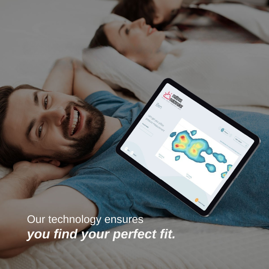 A smiling man lies on a mattress with a tablet displaying a colorful pressure map. Text overlay reads, "Get pressure mapped in-store today, free."-image