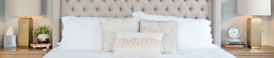An image of a bed with white mattress, white pillows and beige colored cusion